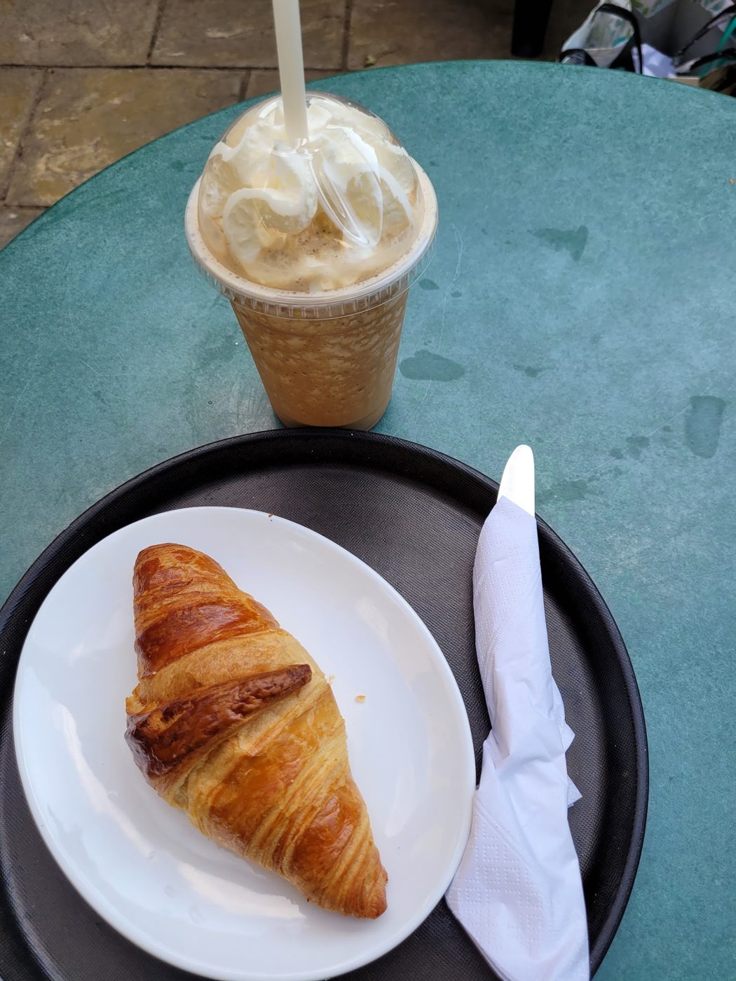 An iced coffee with cream and a croissant