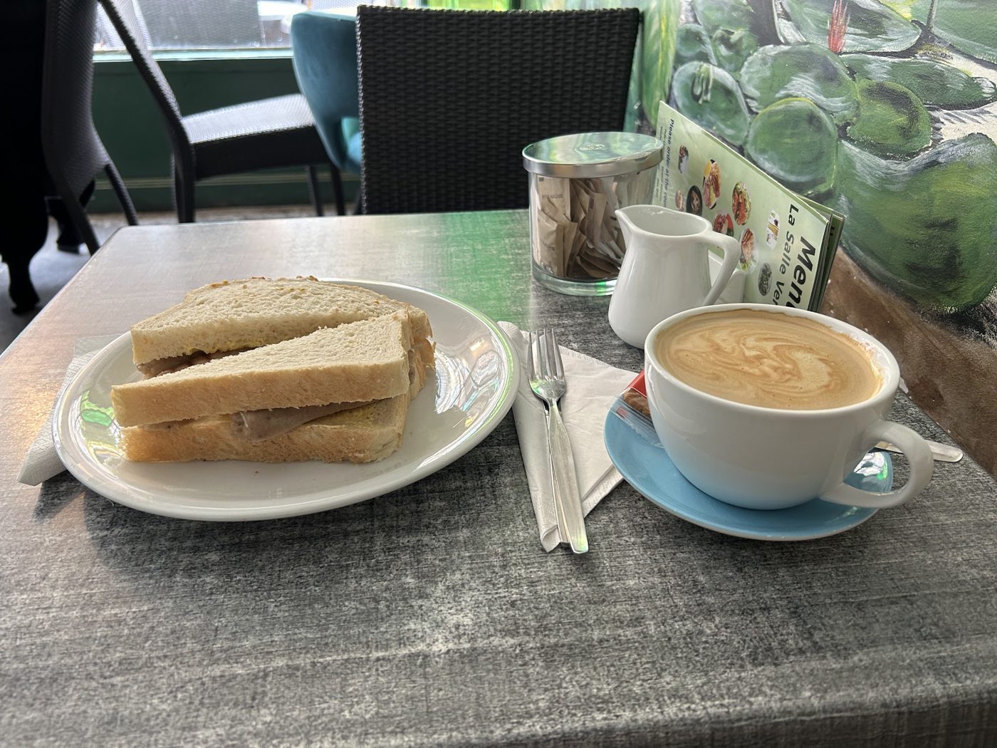 A sandwich and a cup of coffee by the window