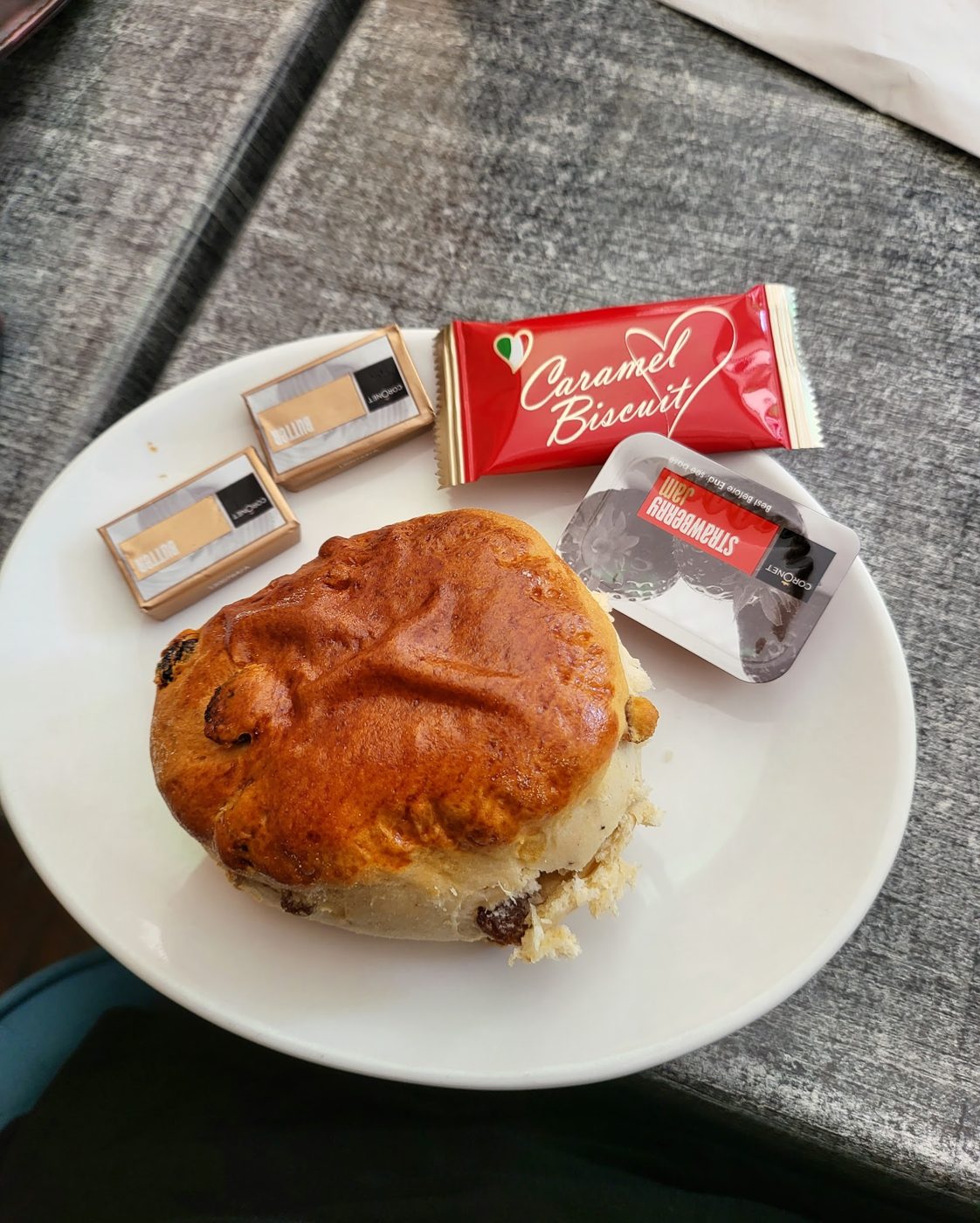 A scone with butter, jam and a caramel biscuit